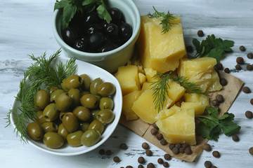Parmesan cheese, fresh herbs and olives on wooden background