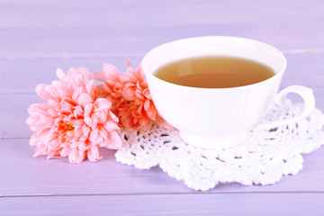 Fototapeta na wymiar Pink chrysanthemums and cup of tea on wooden table