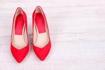 Beautiful red female shoes, on wooden background
