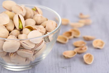 Pistachio nuts in glass bowl on wooden background