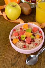 Delicious oatmeal with fruit in bowl on table close-up