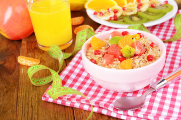 Delicious oatmeal with fruit in bowl on table close-up