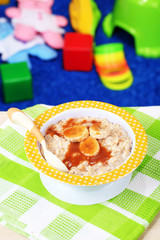 Bowl of porridge for baby and toys  on table, on toys