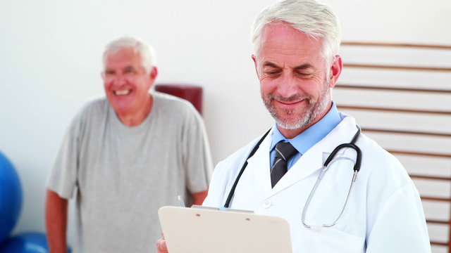 Smiling doctor reading from clipboard