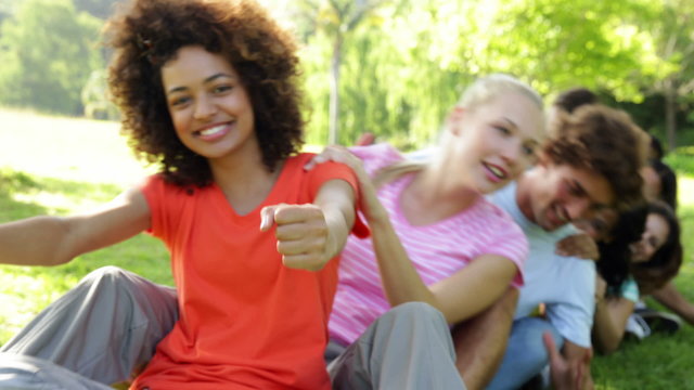 Group of casual young friends sitting in a row messing