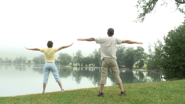 Paar macht Gymnastik  am See mit Nebel