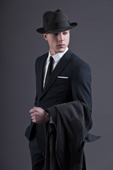 Obraz na płótnie Canvas Retro fashion fifties young businessman with hat wearing dark su