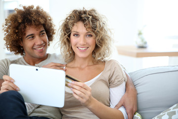 Cheerful couple at home e-shopping with tablet