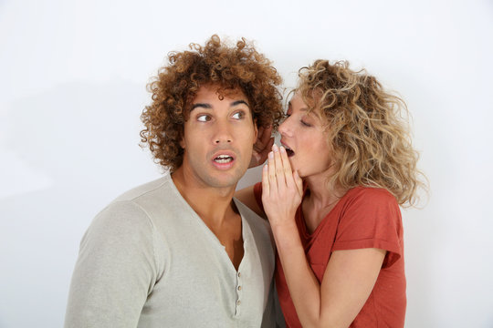Woman telling secret to boyfriend's ear