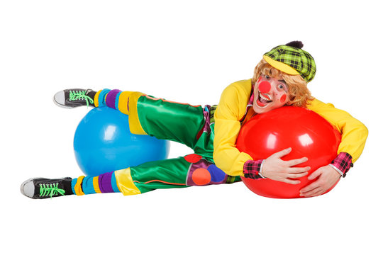 Funny clown lies on balls isolated on white background