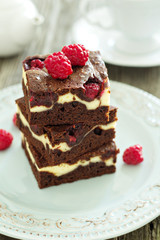 Cheesecake brownies with raspberry stacked on a plate