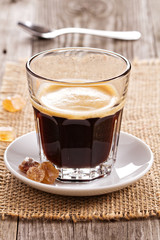 Black coffee in a glass with crystal sugar