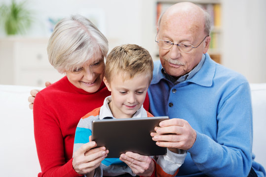 senioren mit enkel schauen auf tablet