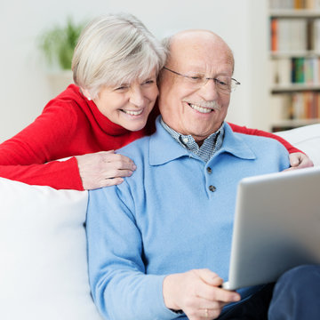 glückliches senioren-paar schaut auf laptop