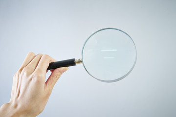Image of right hand holding a magnifying glass, low angle view
