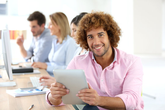 Smiling man in office using digital tablet