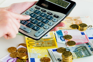 Hand mit Taschenrechner und Geld