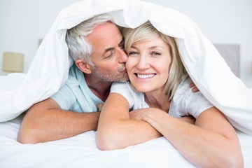 Closeup of mature man kissing womans cheek in bed