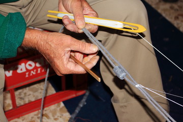 pescatore intento alla riparazione della rete da pesca