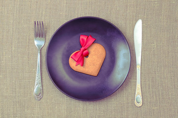 Heart shaped gingerbread cookie on the black plate