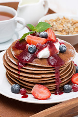 pancakes with cream, fruit sauce and fresh berry on wooden tray