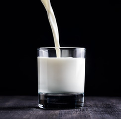 Milk pouring into a glass on black board