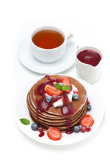 stack of pancakes with cream, fruit sauce, berries and tea