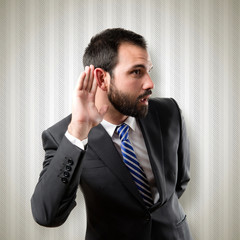 Young business man hearing something over textured background