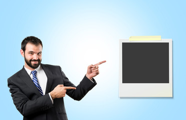 Businessman pointing to a photo over blue background