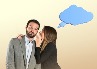 young girl whispering to her boyfriend over ocher background