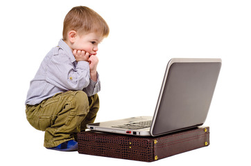 Little boy thoughtfully sits at a laptop