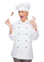 smiling female chef with fork and tomato