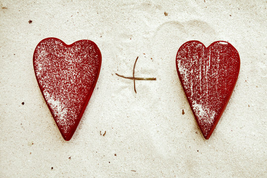Two romantic red  hearts  on the sand