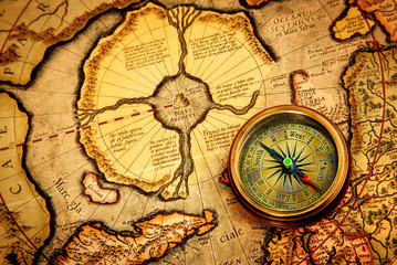 Vintage compass lies on an ancient map of the North Pole.