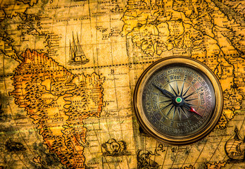 Vintage compass lies on an ancient world map