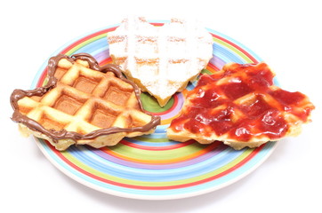 Heart shaped waffles lying on colorful plate. White background