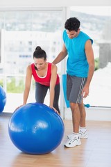 Male trainer helping woman with her exercises at gym