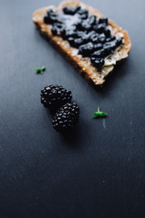Healthy breakfast with blackberry jam with toast on black slate
