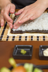 Obraz na płótnie Canvas Woman chef filling japanese sushi rolls with rice