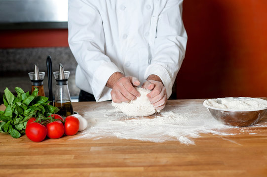 Chef preparing pizza base, cropped image