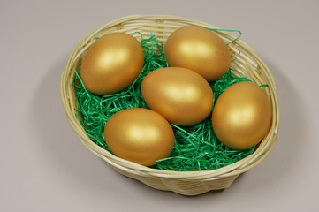 five golden eggs in basket on green grass