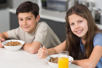 Smiling young siblings enjoying breakfast in kitchen