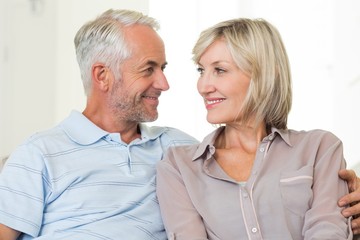 Smiling mature couple sitting on sofa with arm around