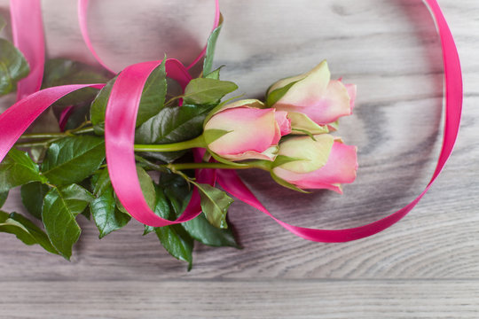 Bouquet of pink roses with ribbon on wood