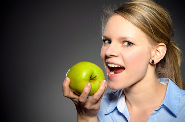 junge blonde Frau mit einem grünen Apfel