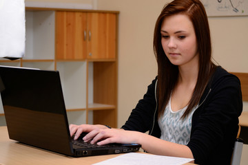 Schuelerin schreibt am Laptop