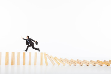 businessman running and catching  on toppling dominoes