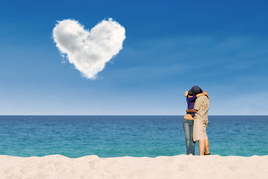 Couple kissing under love cloud at beach