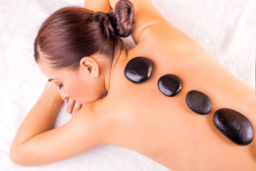 Obraz na płótnie Canvas woman in spa salon with hot stones