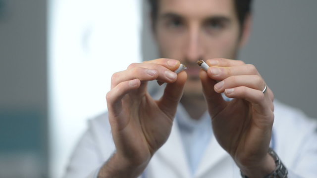 Young friendly doctor breaking a cigarette, quitting smoking con